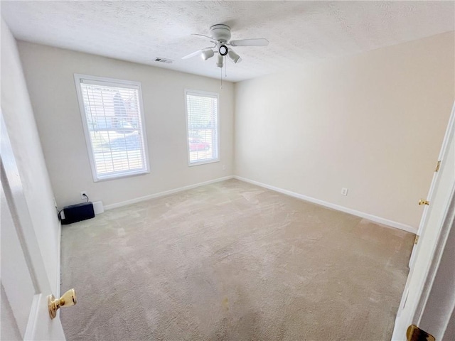 spare room featuring carpet floors, ceiling fan, a textured ceiling, and visible vents