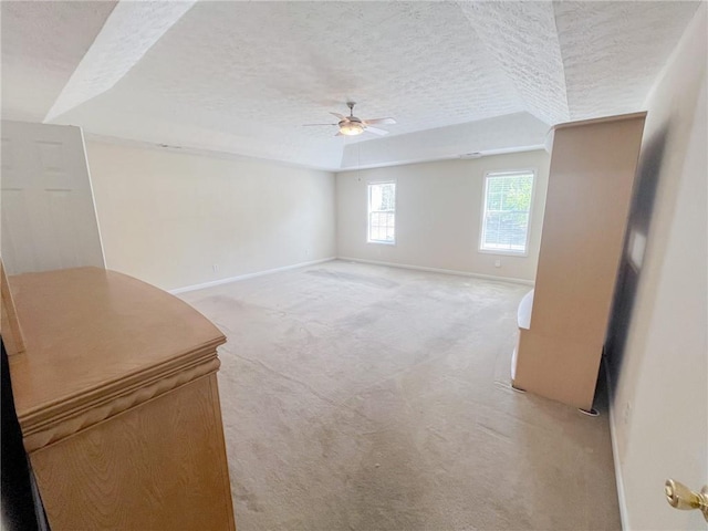 spare room featuring baseboards, a ceiling fan, a textured ceiling, and light carpet
