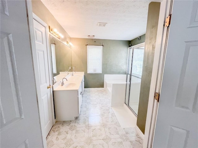 bathroom with a sink, double vanity, a textured ceiling, visible vents, and a garden tub