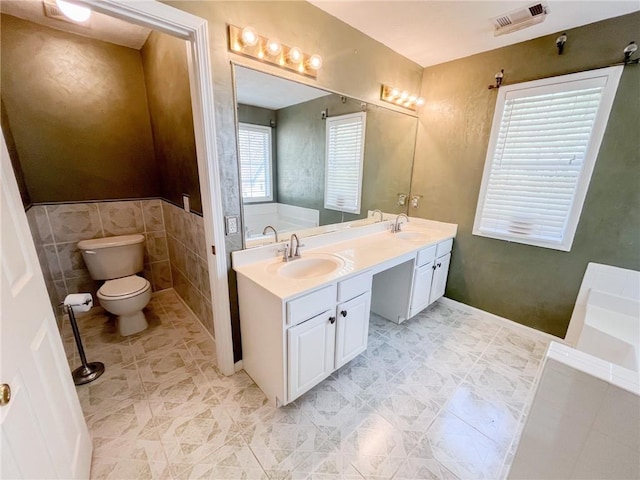 bathroom with a sink, toilet, double vanity, and visible vents