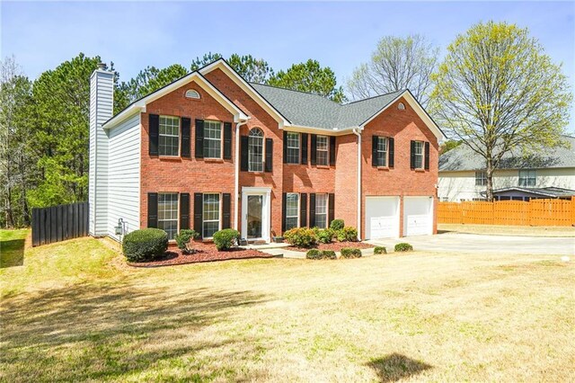 colonial home with concrete driveway, fence, a chimney, and a garage