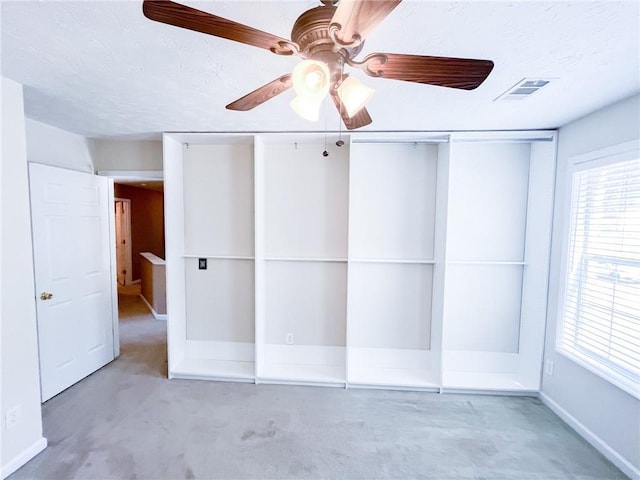 unfurnished bedroom featuring a textured ceiling, baseboards, visible vents, and ceiling fan