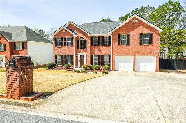 colonial inspired home with a front yard, a garage, brick siding, fence, and concrete driveway