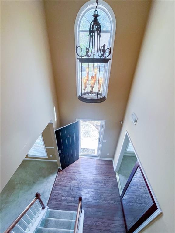 entryway with wood finished floors, a high ceiling, a notable chandelier, and a healthy amount of sunlight