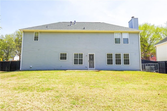 rear view of property with a lawn, central AC, fence, and a chimney