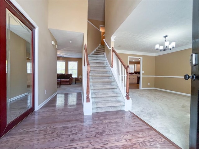 entryway featuring stairway, baseboards, an inviting chandelier, and crown molding