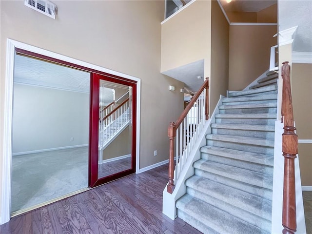 stairs with baseboards, wood finished floors, and visible vents