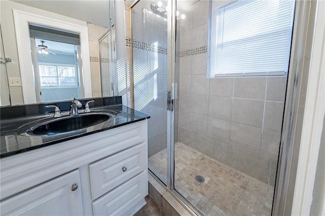 bathroom featuring a shower with shower door, vanity, and ceiling fan