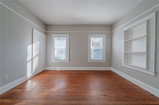 unfurnished room featuring dark hardwood / wood-style floors and built in shelves