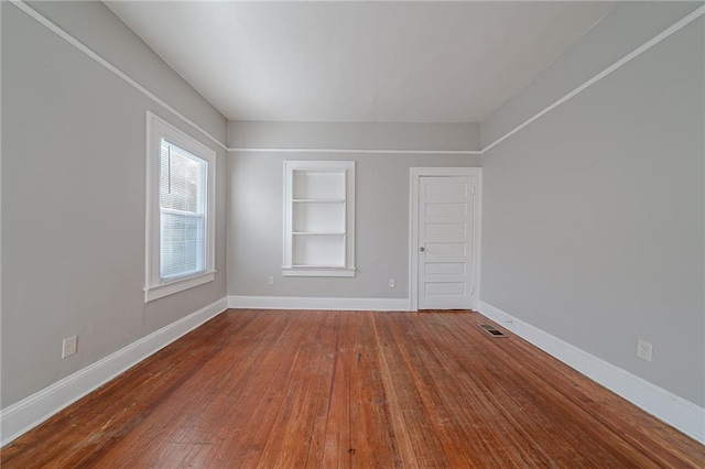 empty room featuring built in features and wood-type flooring