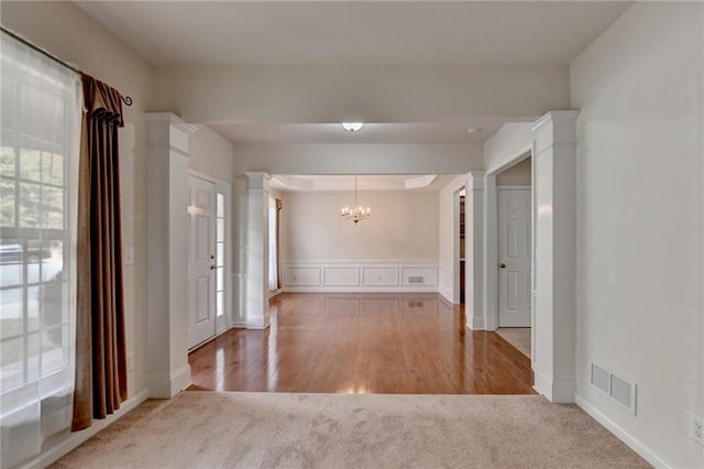 entryway with hardwood / wood-style flooring, a chandelier, and ornate columns