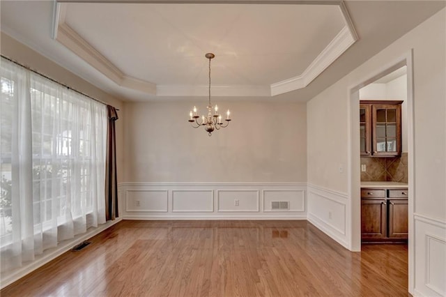 unfurnished dining area featuring light hardwood / wood-style flooring and a tray ceiling