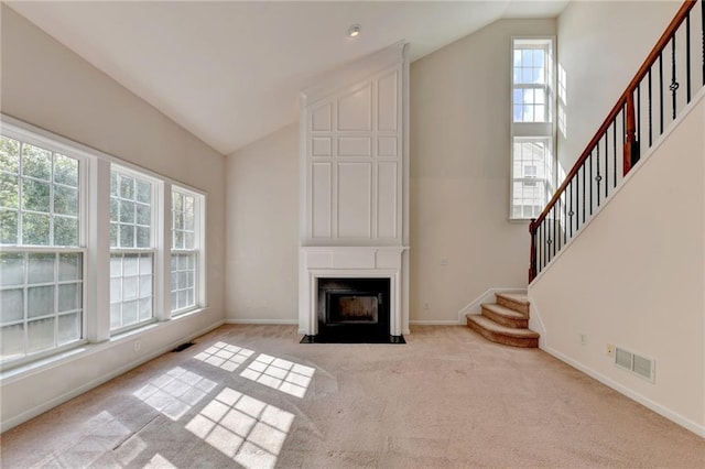 unfurnished living room with light carpet, lofted ceiling, and a large fireplace