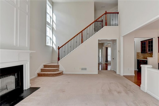 carpeted living room featuring a healthy amount of sunlight and a towering ceiling