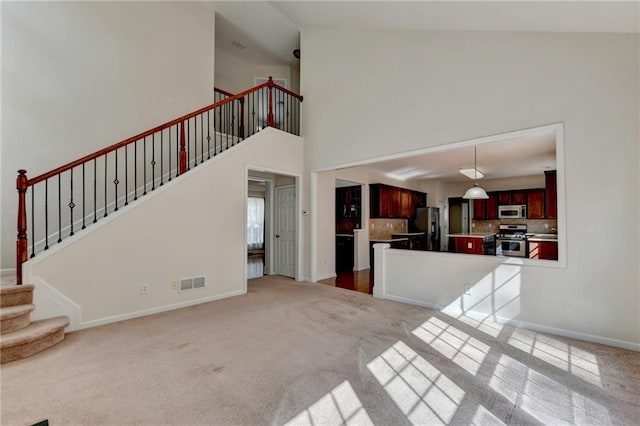 unfurnished living room featuring carpet and a high ceiling