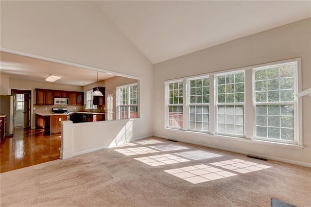 interior space featuring high vaulted ceiling, carpet flooring, and a healthy amount of sunlight