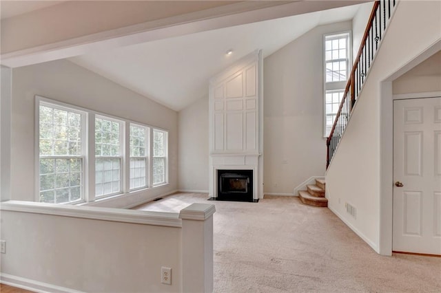 unfurnished living room with lofted ceiling, light colored carpet, and a large fireplace