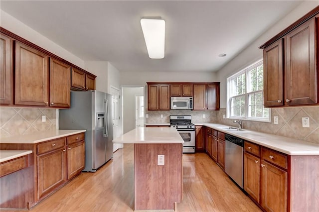 kitchen featuring decorative backsplash, a kitchen island, appliances with stainless steel finishes, light hardwood / wood-style floors, and sink