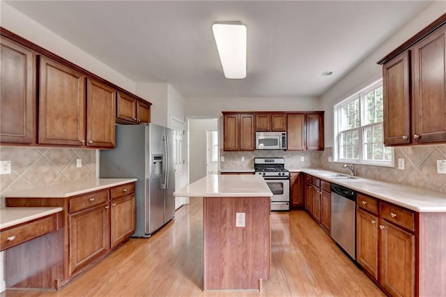 kitchen with a kitchen island, appliances with stainless steel finishes, decorative backsplash, and light wood-type flooring