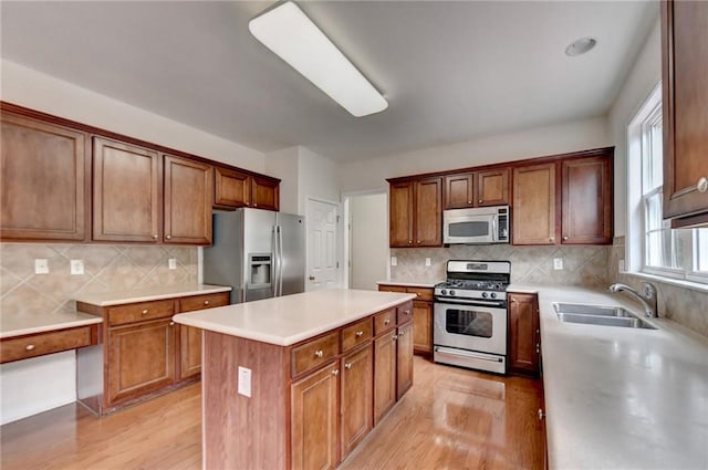 kitchen featuring light hardwood / wood-style flooring, stainless steel appliances, backsplash, sink, and a center island