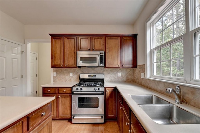 kitchen with a wealth of natural light, sink, stainless steel appliances, and light wood-type flooring