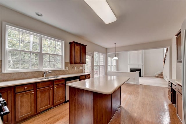 kitchen with hanging light fixtures, a kitchen island, light hardwood / wood-style flooring, dishwasher, and sink