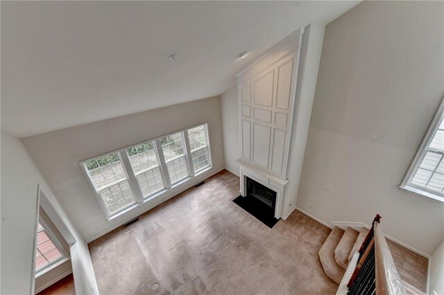 living room with light carpet, high vaulted ceiling, and plenty of natural light