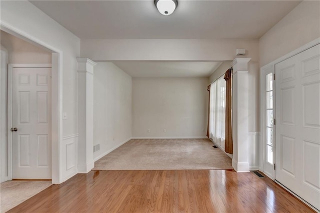 entryway featuring light hardwood / wood-style floors, ornate columns, and a wealth of natural light