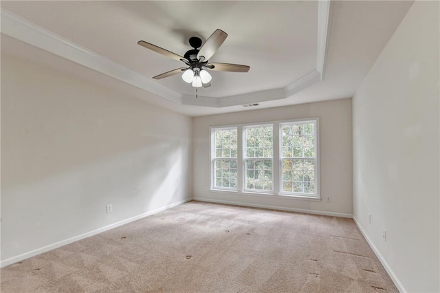 spare room featuring ceiling fan, light colored carpet, and a raised ceiling