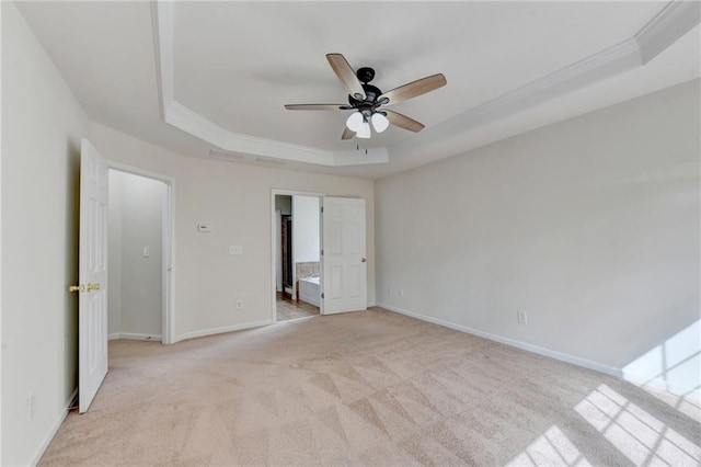 unfurnished bedroom featuring light carpet, a tray ceiling, ensuite bath, crown molding, and ceiling fan