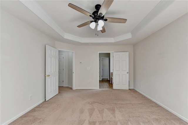 unfurnished bedroom with ceiling fan, a raised ceiling, ornamental molding, and light colored carpet