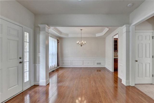 foyer featuring ornate columns, a healthy amount of sunlight, and light wood-type flooring