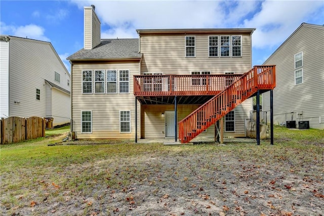 rear view of property with a yard, a deck, and central air condition unit