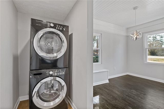 laundry area with stacked washer and dryer, dark wood-type flooring, a chandelier, and plenty of natural light