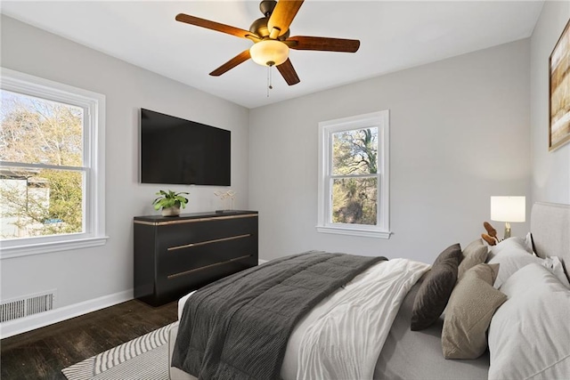 bedroom featuring multiple windows, ceiling fan, and dark hardwood / wood-style flooring