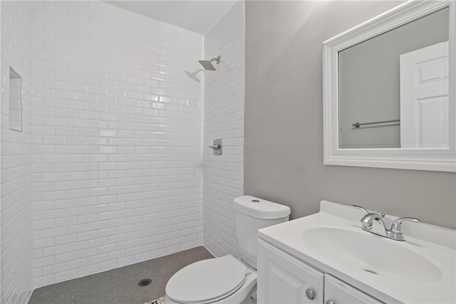 bathroom with vanity, toilet, and a tile shower