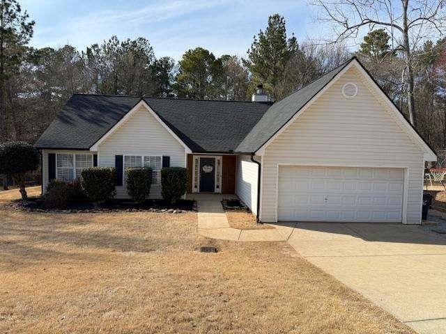 ranch-style home featuring concrete driveway, a front lawn, a chimney, and an attached garage