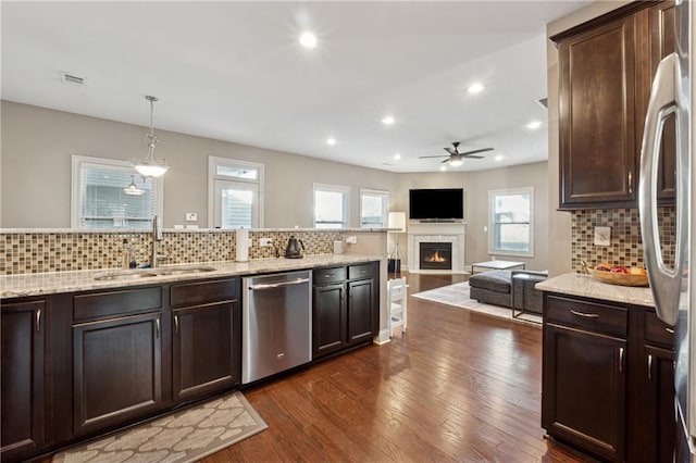 kitchen featuring decorative light fixtures, stainless steel appliances, sink, backsplash, and ceiling fan