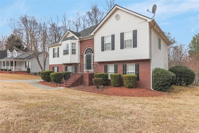 split foyer home featuring brick siding and a front lawn