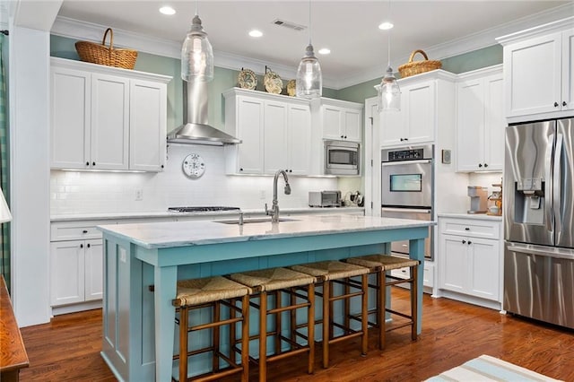 kitchen with stainless steel appliances, decorative light fixtures, white cabinetry, a kitchen bar, and a kitchen island with sink