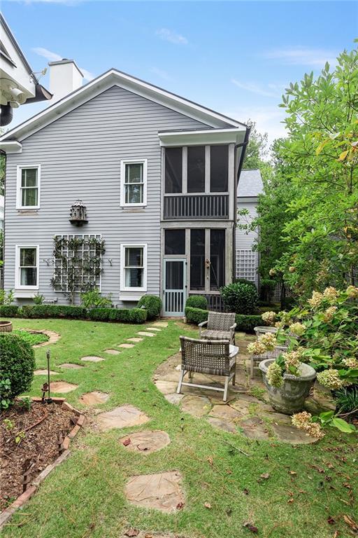 rear view of house featuring a patio area, a lawn, and a sunroom