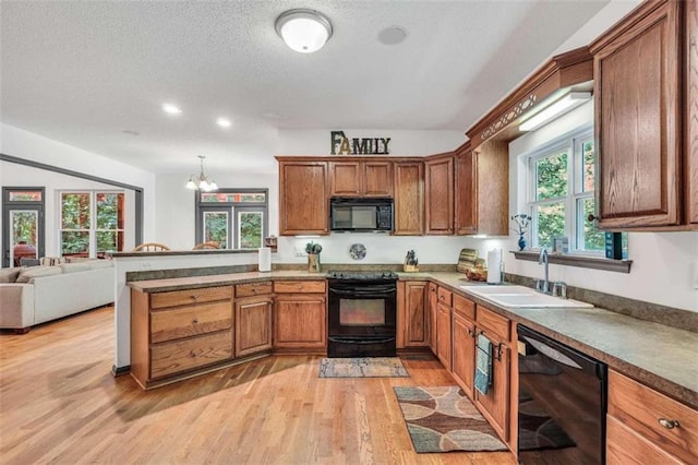 kitchen featuring brown cabinets, black appliances, light wood-style floors, and a sink