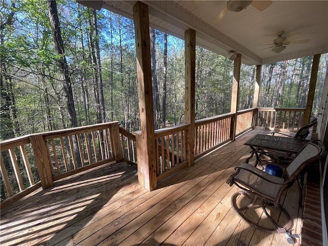 wooden deck with a wooded view and ceiling fan