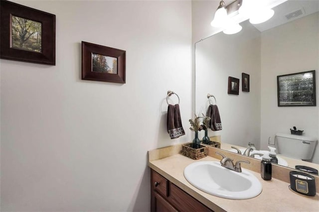 half bath featuring visible vents, toilet, and vanity