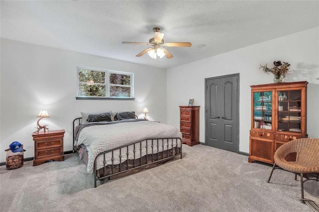 carpeted bedroom featuring a ceiling fan, a closet, baseboards, and a textured ceiling