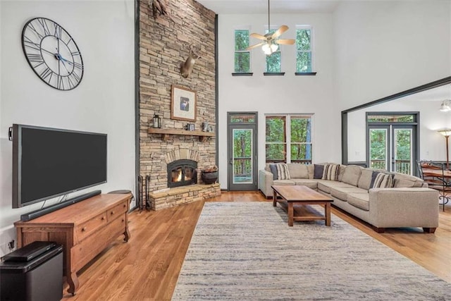 living room featuring french doors, a ceiling fan, a fireplace, and wood finished floors