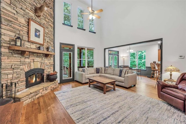 living room with ceiling fan with notable chandelier, a fireplace, and wood finished floors