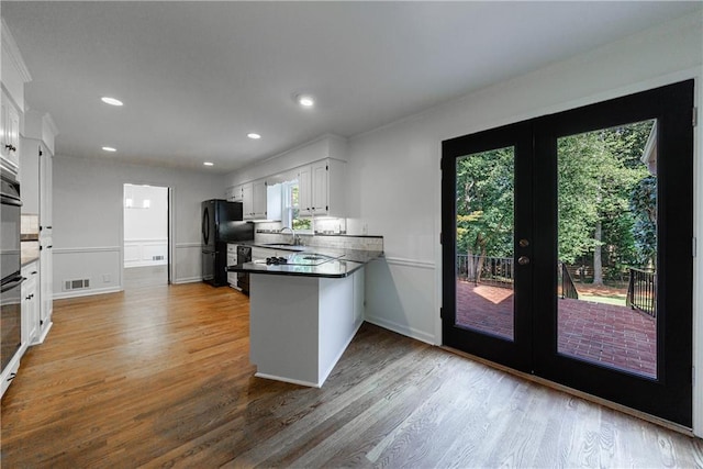 5004 Haralson Way SW, Lilburn, GA 30047 - kitchen featuring french doors, wood finished floors, a peninsula, white cabinets, and recessed lighting