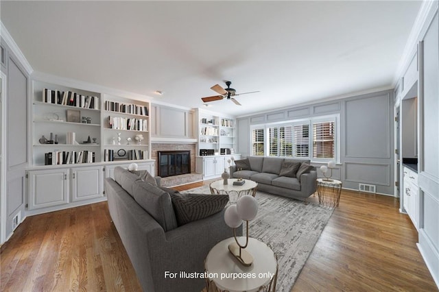 5004 Haralson Way SW, Lilburn, GA 30047 - living area with a decorative wall, wood finished floors, built in shelves, ceiling fan, and a glass covered fireplace