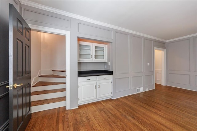5004 Haralson Way SW, Lilburn, GA 30047 - interior space featuring a decorative wall, wood finished floors, ornamental molding, dark countertops, and glass insert cabinets